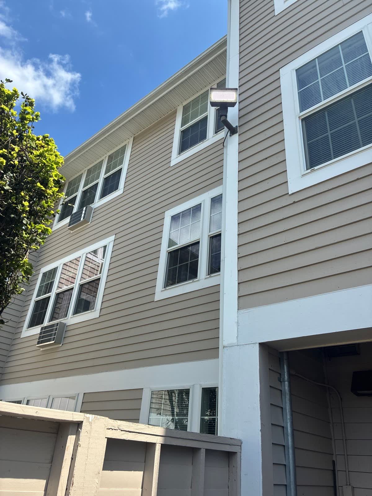 Upward view of siding, windows, corner trim, soffit, and an exterior light
