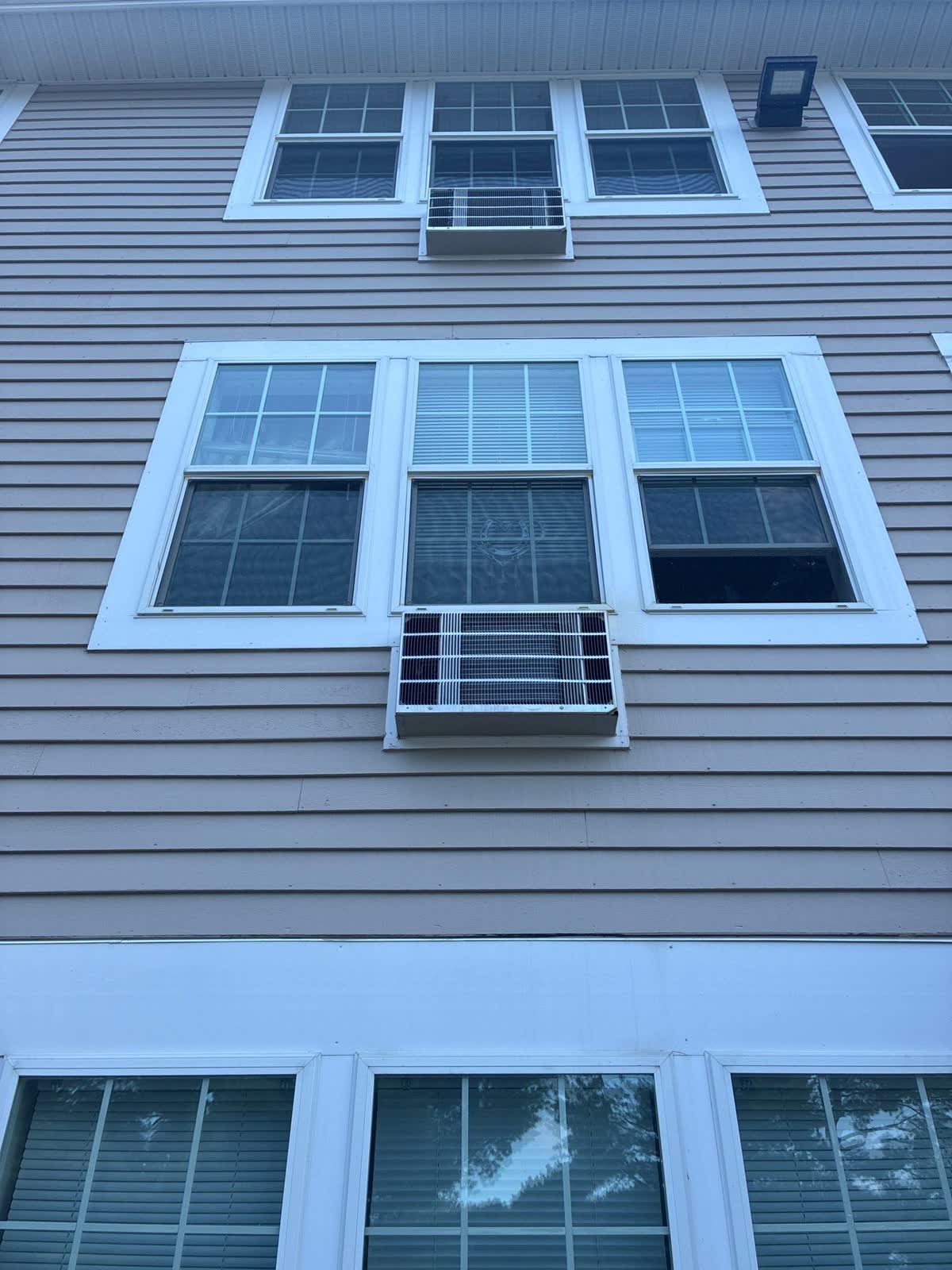 Close field view of exterior windows, trim, siding, and window air conditioners